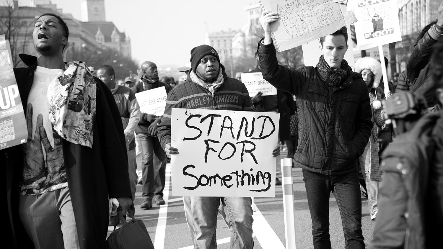 Protestor with "Stand for something" poster