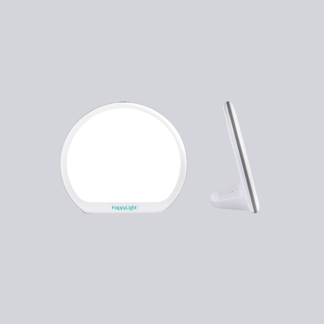 A round, white LED light therapy lamp with "HappyLight" text on the base. The front view shows the bright light; the side view emphasizes its sleek design.